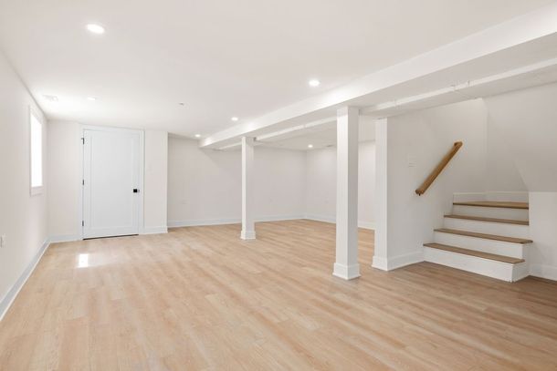 An empty basement with wooden floors and stairs.