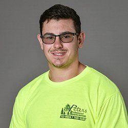 Man wearing glasses and yellow shirt with landscaping logo, smiling.