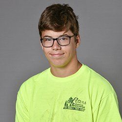 Young man wearing glasses and a neon yellow shirt smiling, with a logo for 