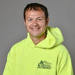 Man in a yellow hoodie smiling, the logo of Peters Professional Landscaping is visible.