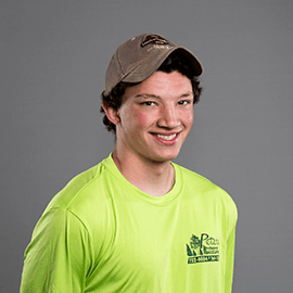 Smiling young man in neon green shirt and cap.