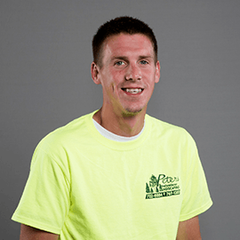Man wearing neon yellow t-shirt with company logo, smiling against a gray backdrop.