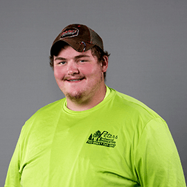 Man wearing a brown cap and bright yellow shirt with a logo, smiling at the camera.