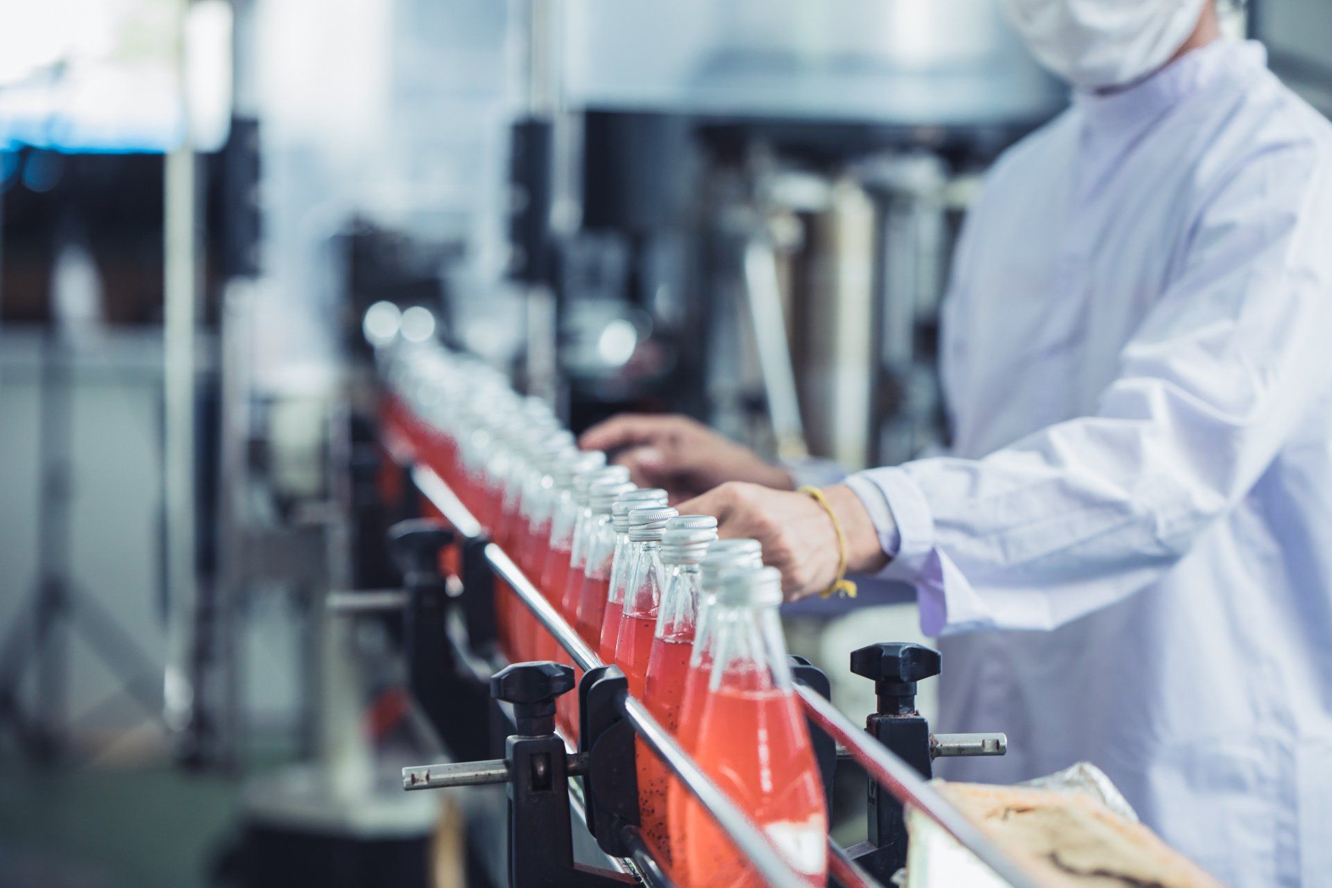 A man wearing a mask is working on a conveyor belt in a factory.