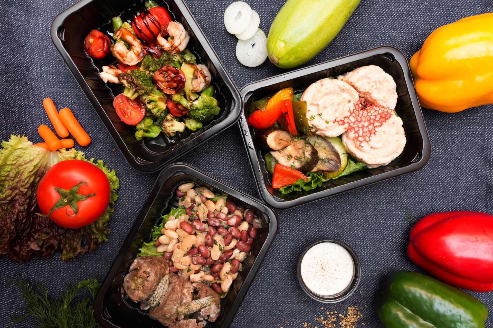 A table topped with containers of food and vegetables.