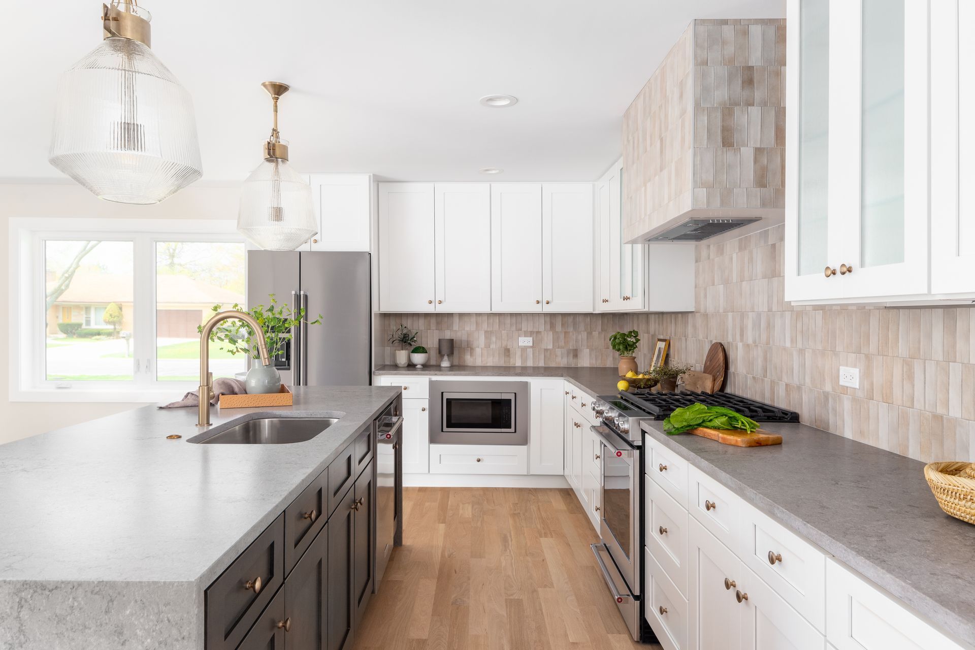 A kitchen with white cabinets , granite counter tops , stainless steel appliances and a large island.