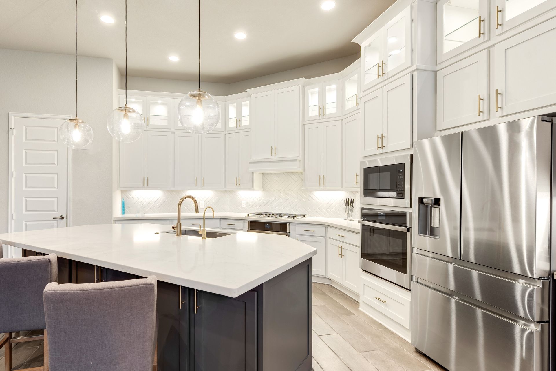 A kitchen with white cabinets , stainless steel appliances and a large island.