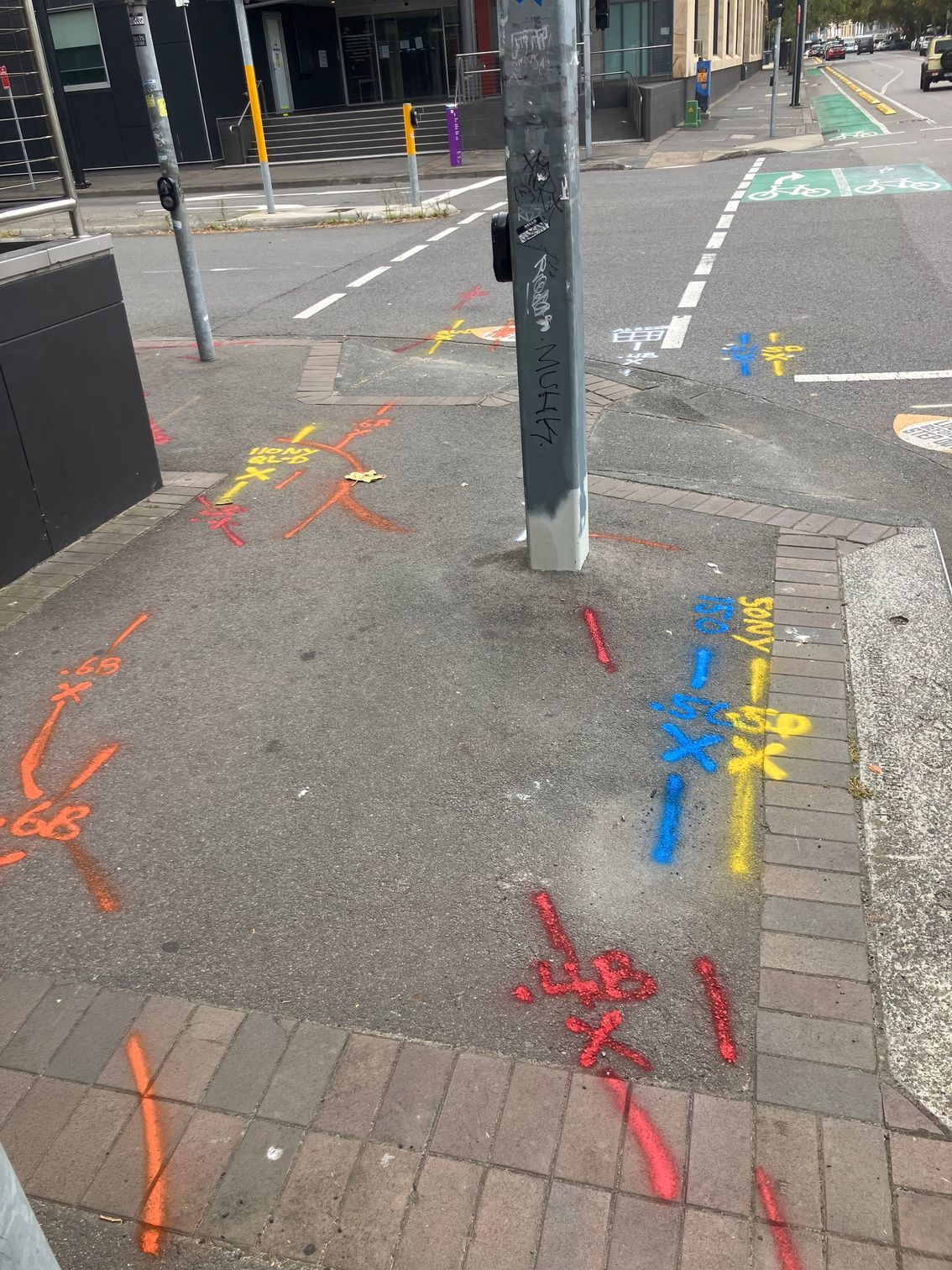 A corner of a street with graffiti on the sidewalk.