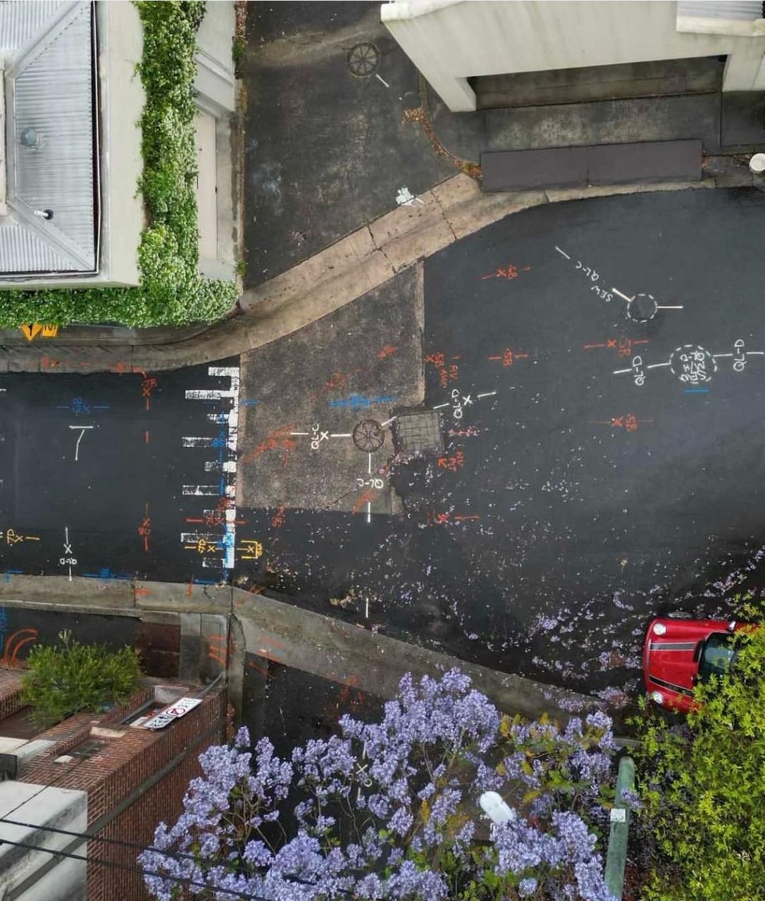 An aerial view of a street with a red car in the middle