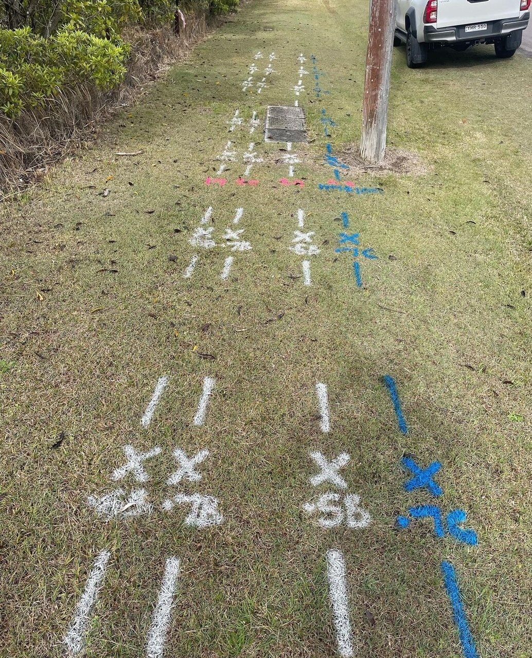 A white truck is parked on the side of the road next to a grassy field.