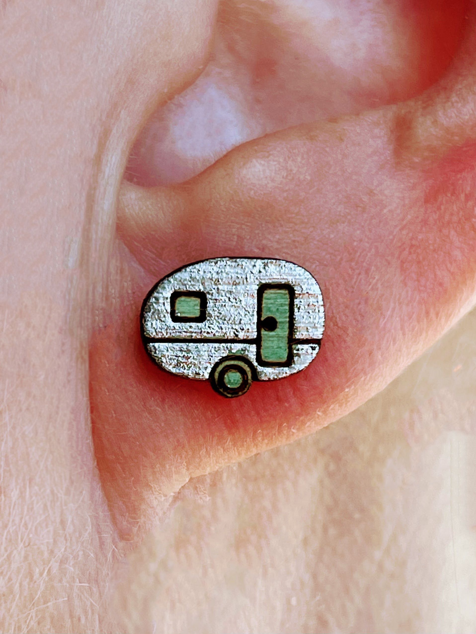 A close up of a person 's ear with a pair of earrings in the shape of a trailer.