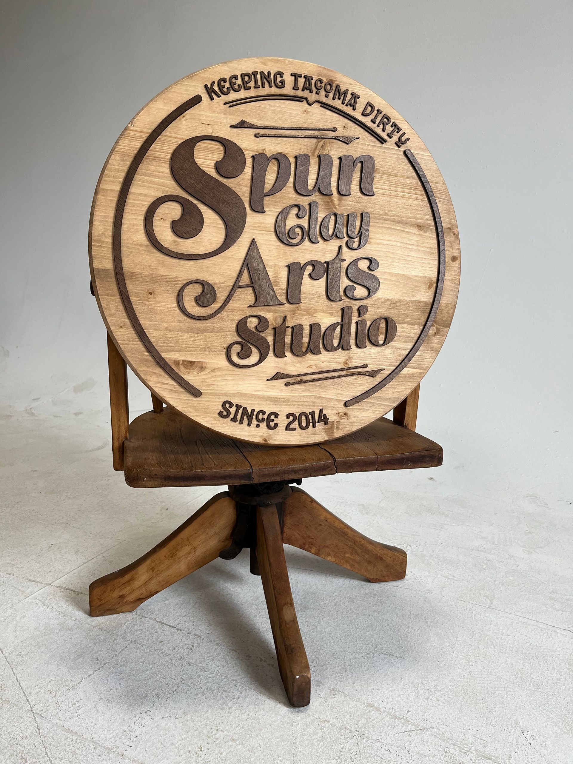 A wooden chair with a sign on it that says spin clay arts studio