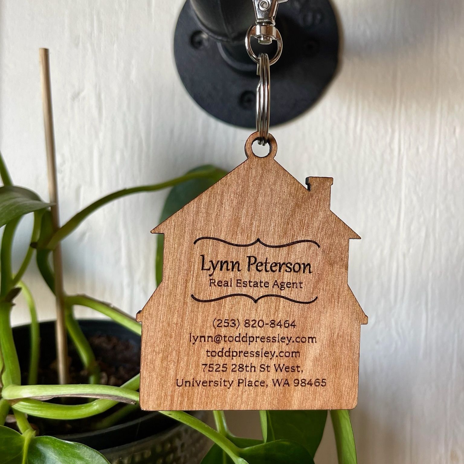 A lynn peterson real estate agent keychain hangs on a plant