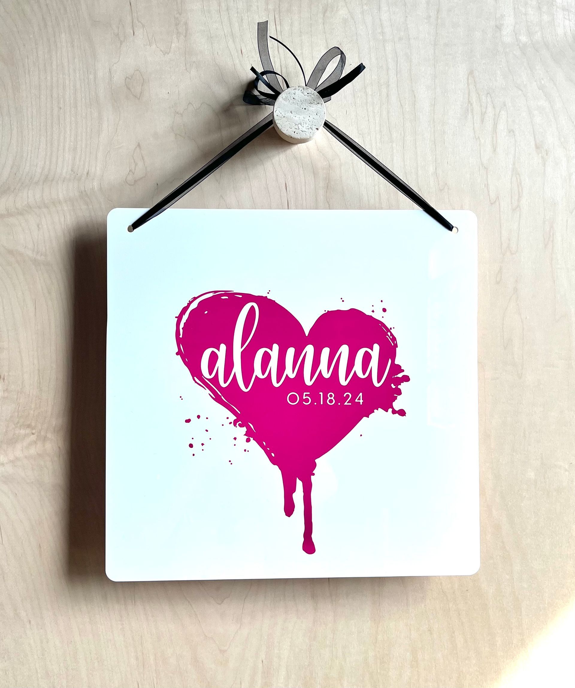 A white sign with a pink heart and the name alanna on it