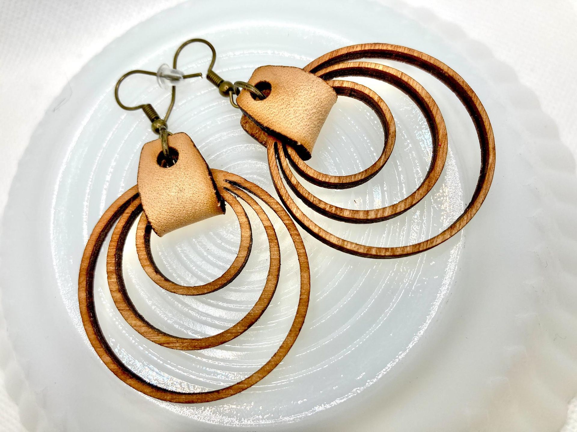 A pair of wooden hoop earrings are sitting on a white plate.