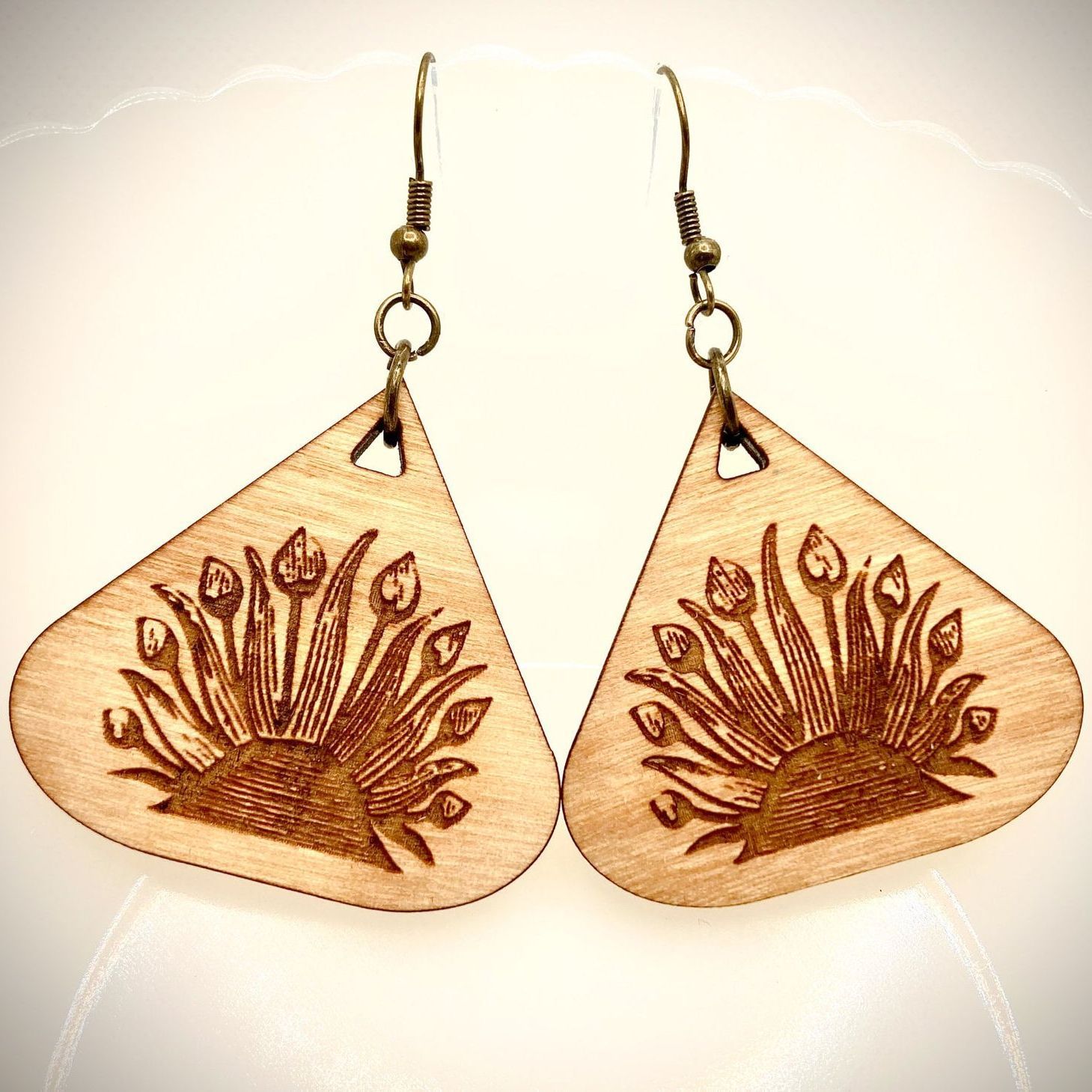 A pair of wooden earrings with a peacock design on them