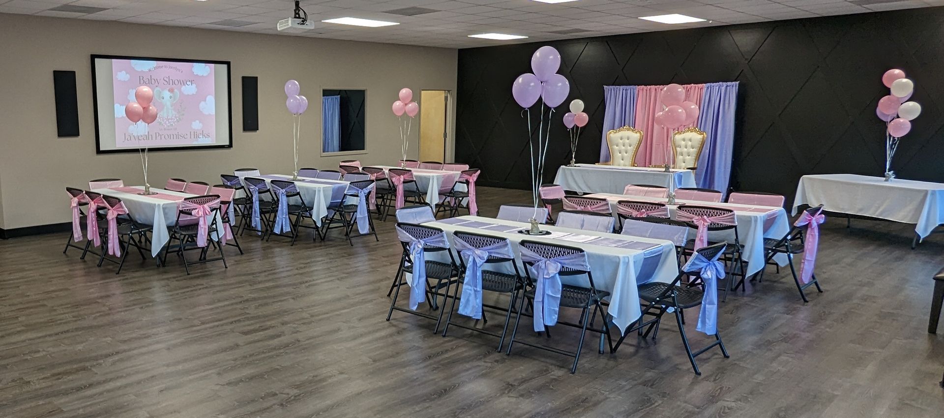 Venue showing tables and chair after decorations. Decorations are purple and pink with balloon centerpieces at each table.