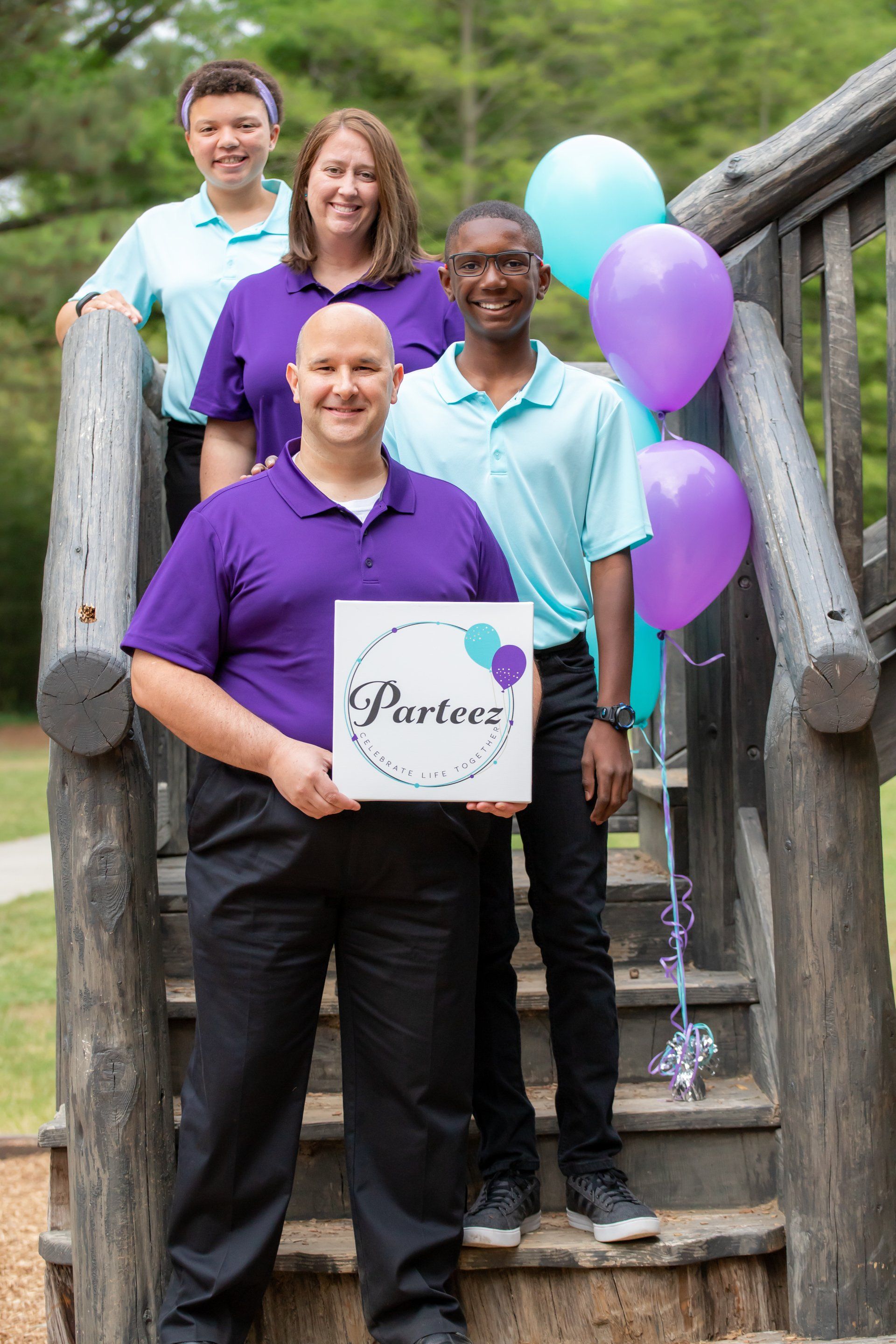 Photo of David, Patricia, Jennica and Micah on wooden stairs with teal and purple balloons symbolizing the Parteez logo