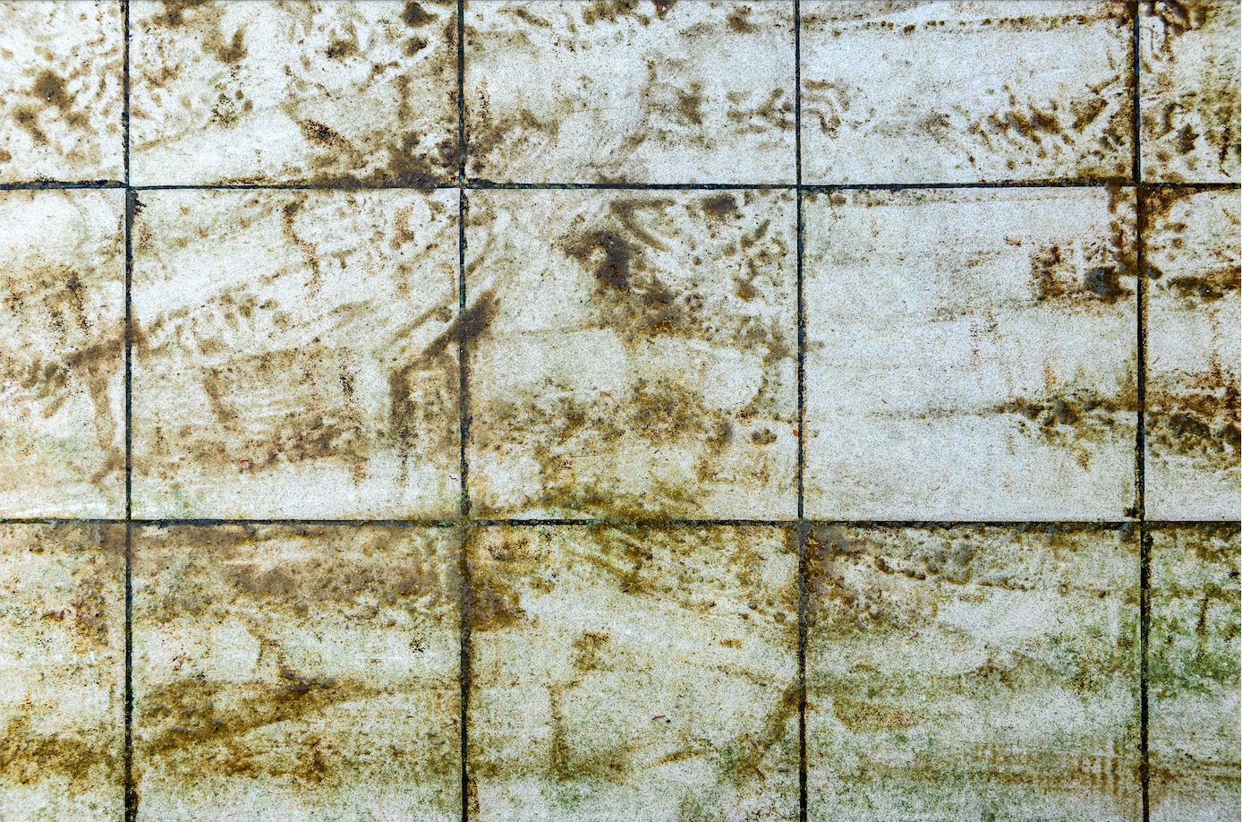 A close up of a dirty tile floor with stains on it.