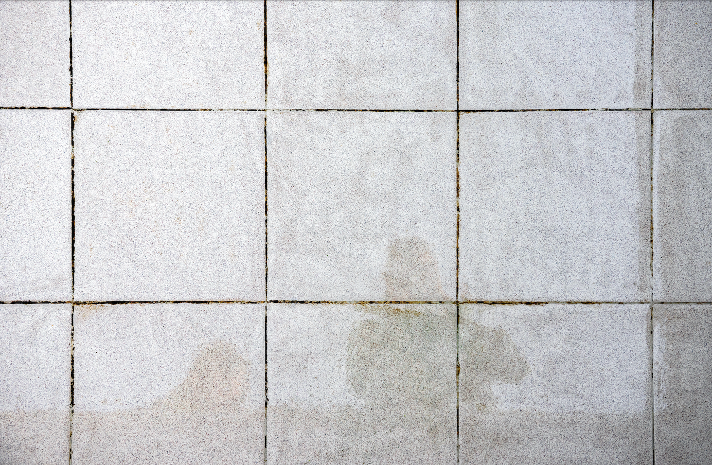 A close up of a tiled floor with stains on it.