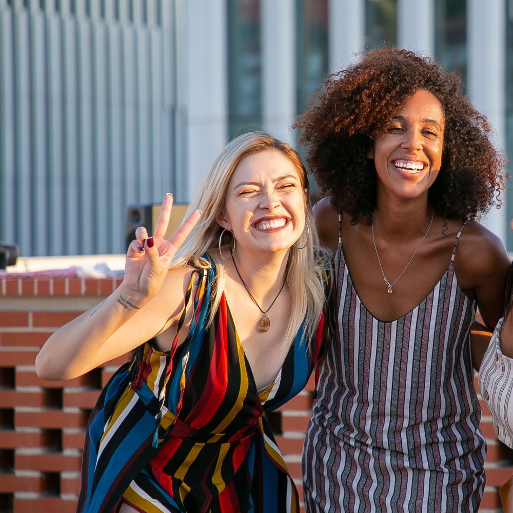 Two women are posing for a picture and one is giving a peace sign