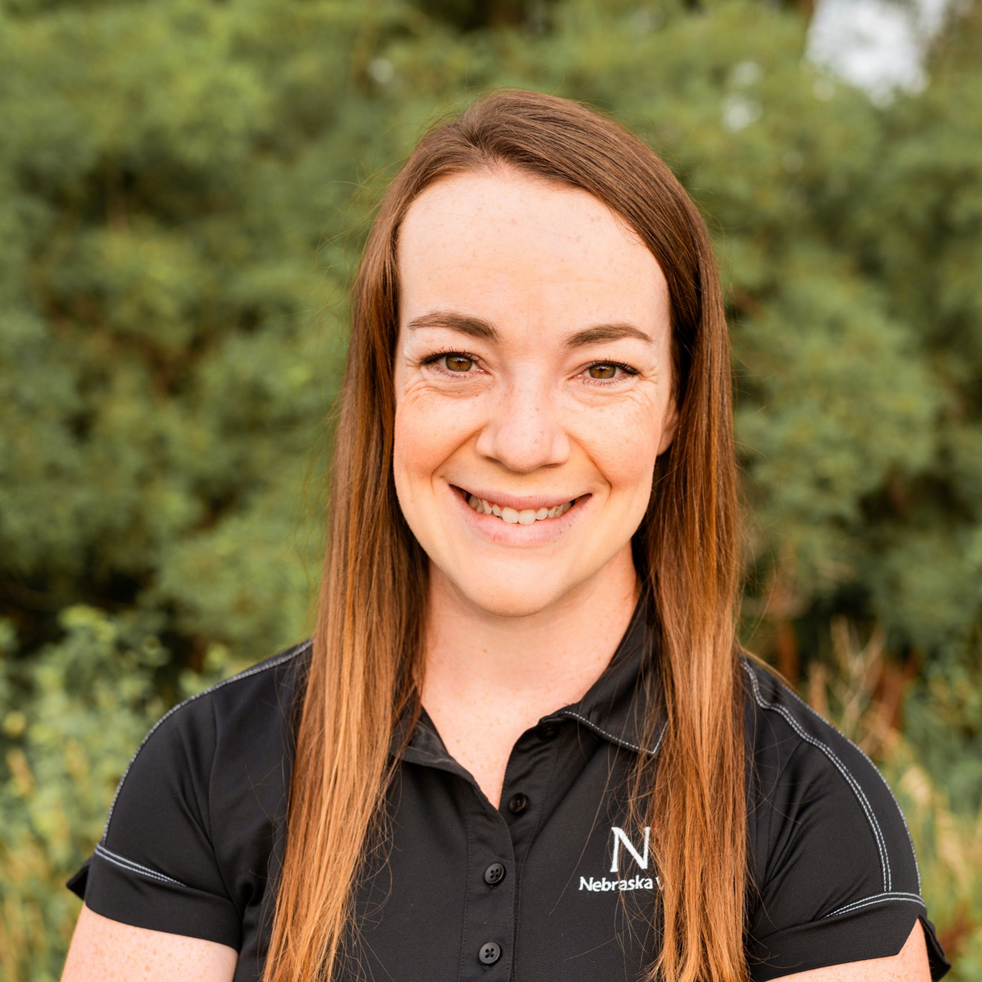 A woman is wearing a stethoscope around her neck and smiling.