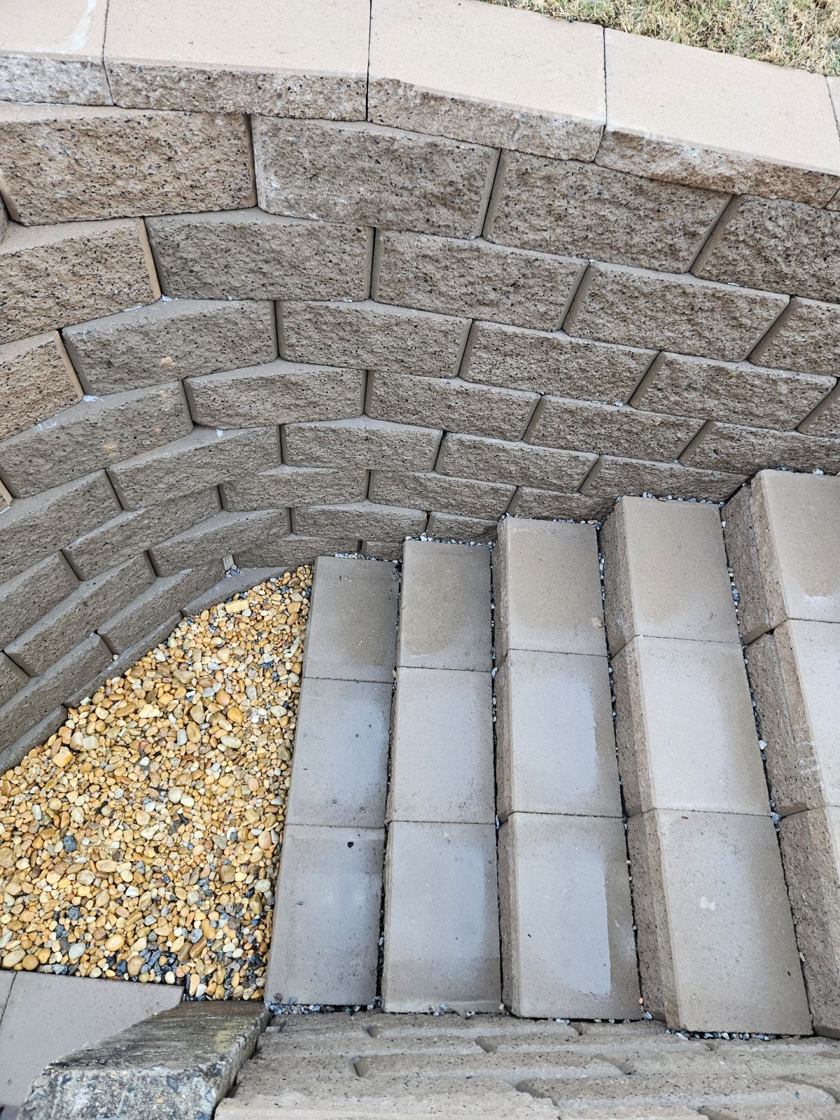 A brick wall with stairs and gravel next to it.