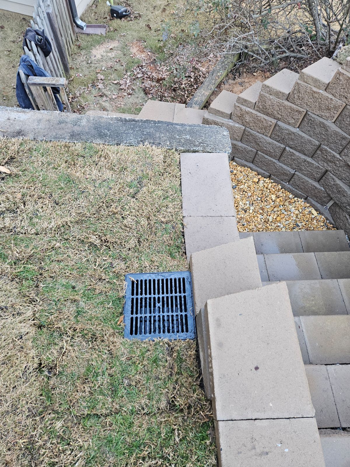 A blue drain is sitting on the side of a staircase next to a brick wall.