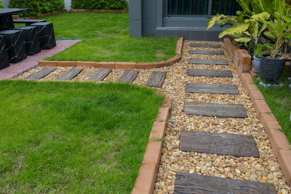 A stone walkway leading to a house in a garden.