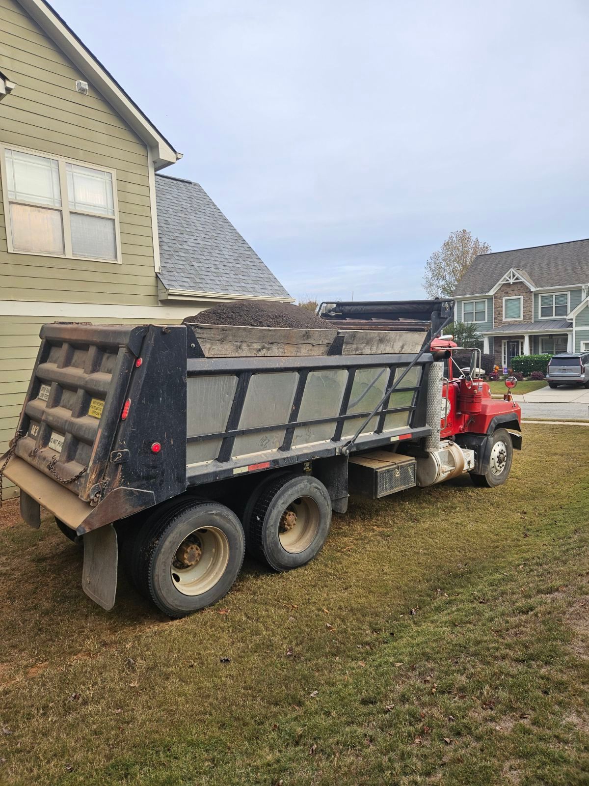 A red dump truck is parked in front of a house.