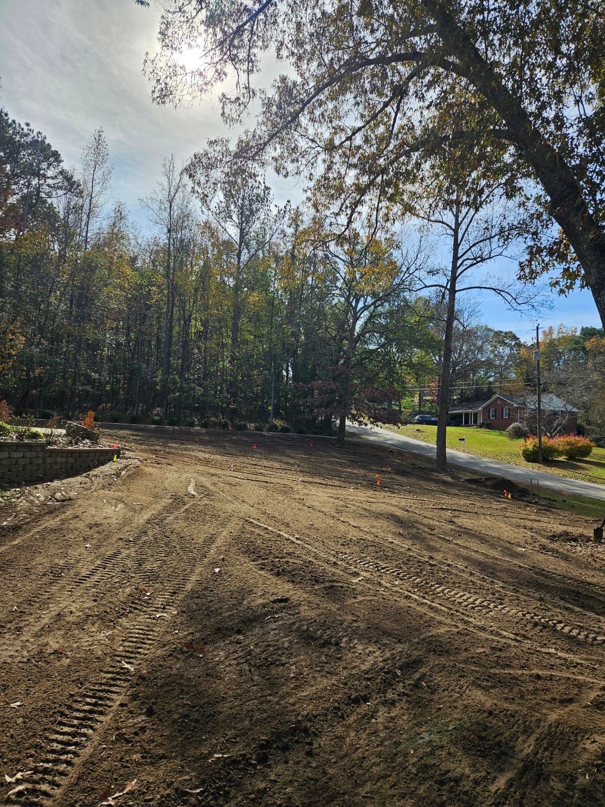 A dirt field with trees and a road in the background.