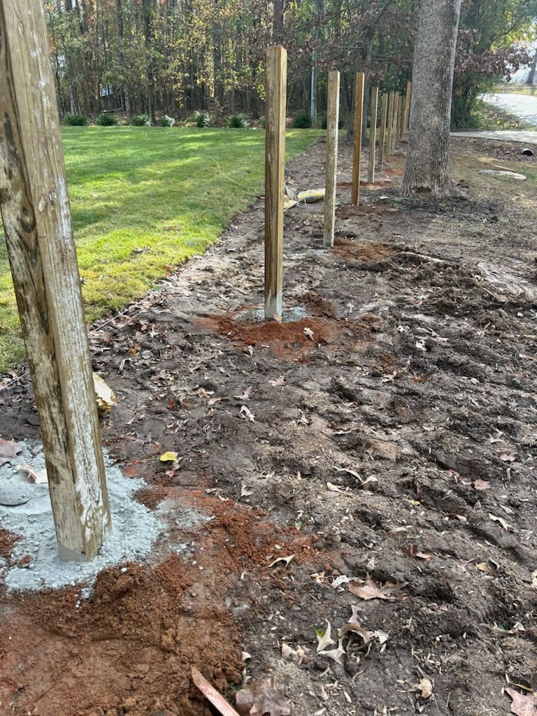 A wooden fence is being built in the middle of a dirt field.