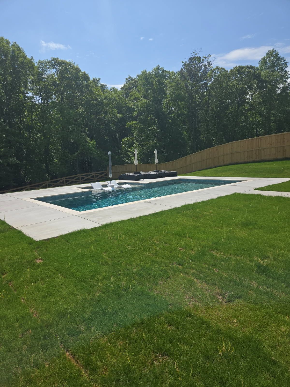 A large swimming pool is in the middle of a lush green field.