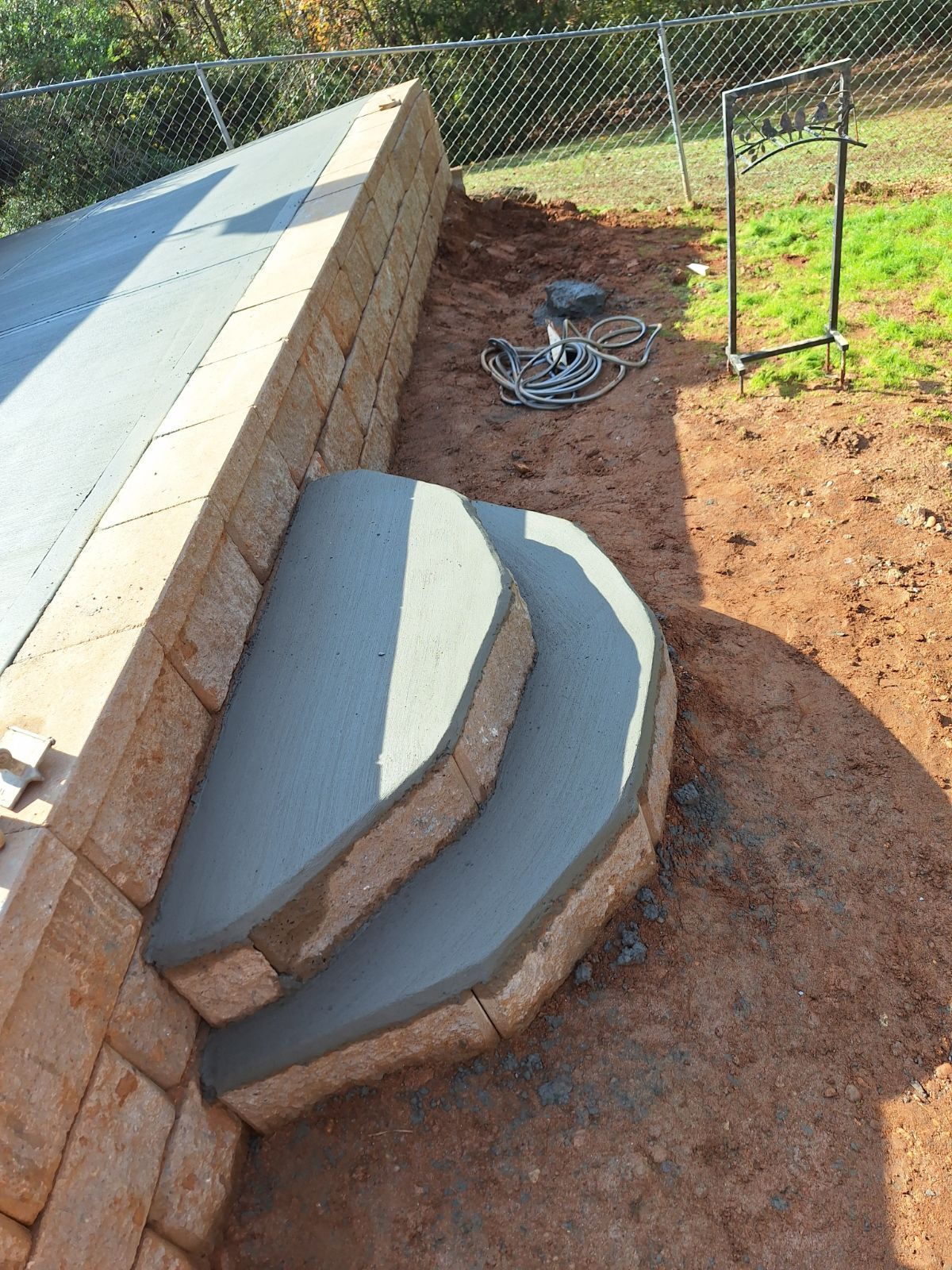 A concrete staircase is being built next to a stone wall.
