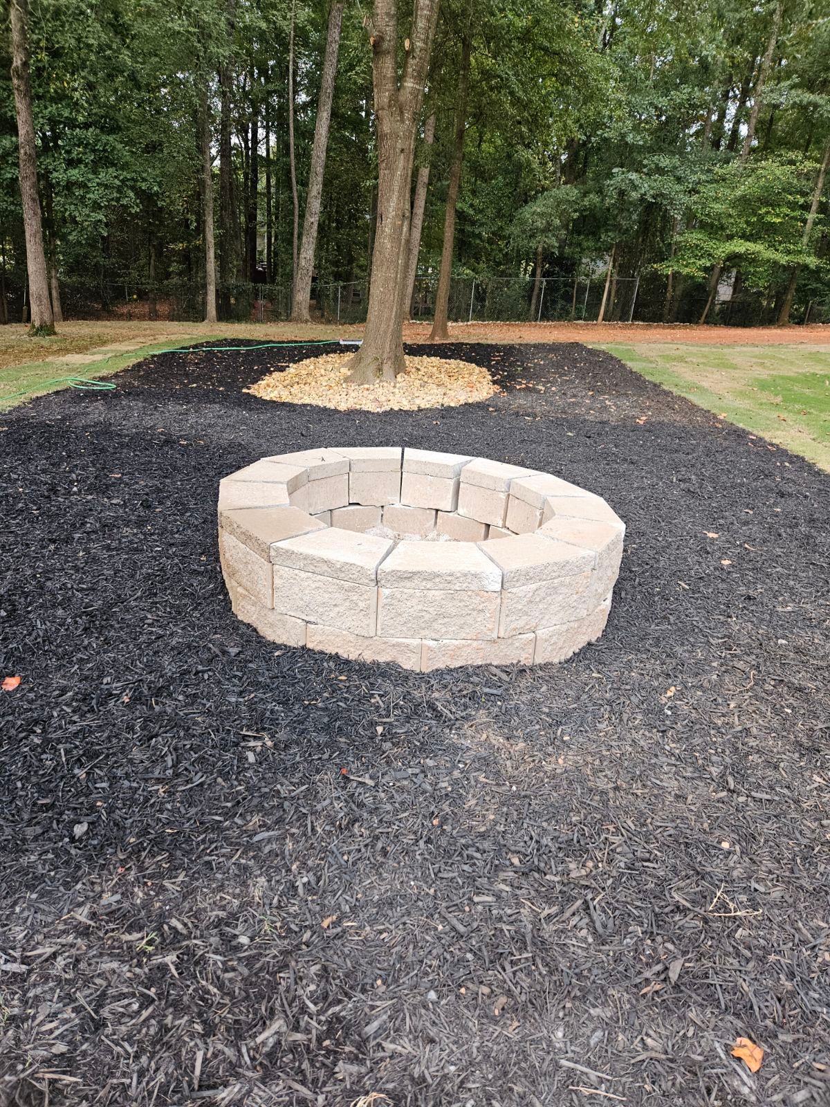 A fire pit is sitting in the middle of a pile of mulch.