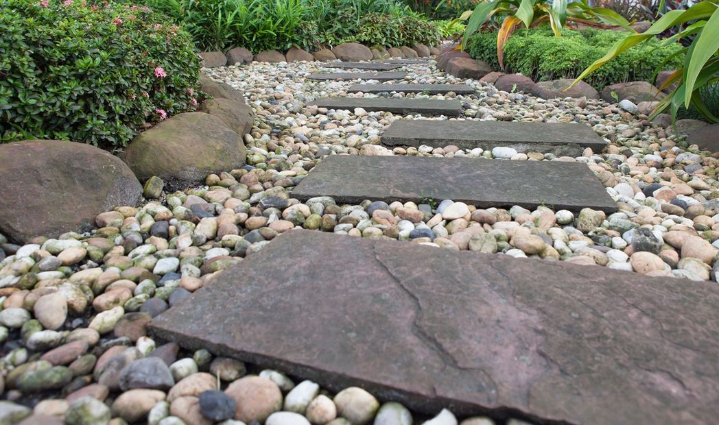 A wooden staircase in a garden surrounded by rocks and plants.