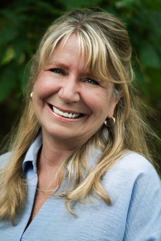 Kim Kinsella, Asheville NC realtor, standing in front of green trees