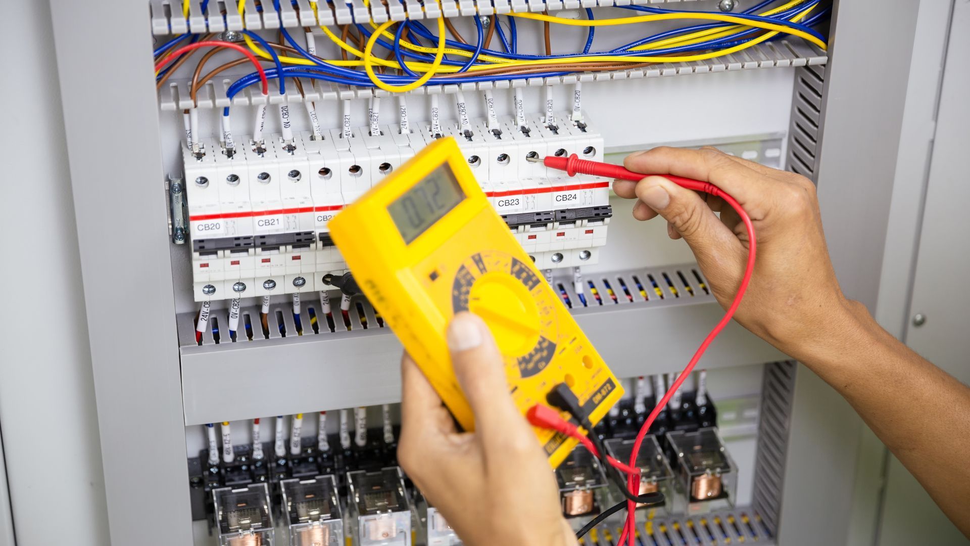 A person is using a digital multimeter to test a circuit board.