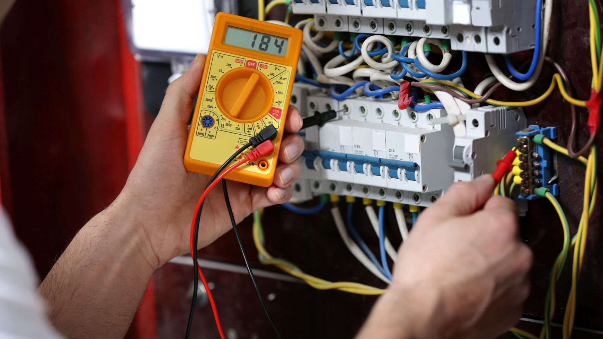 An electrician is using a multimeter to test a circuit board.