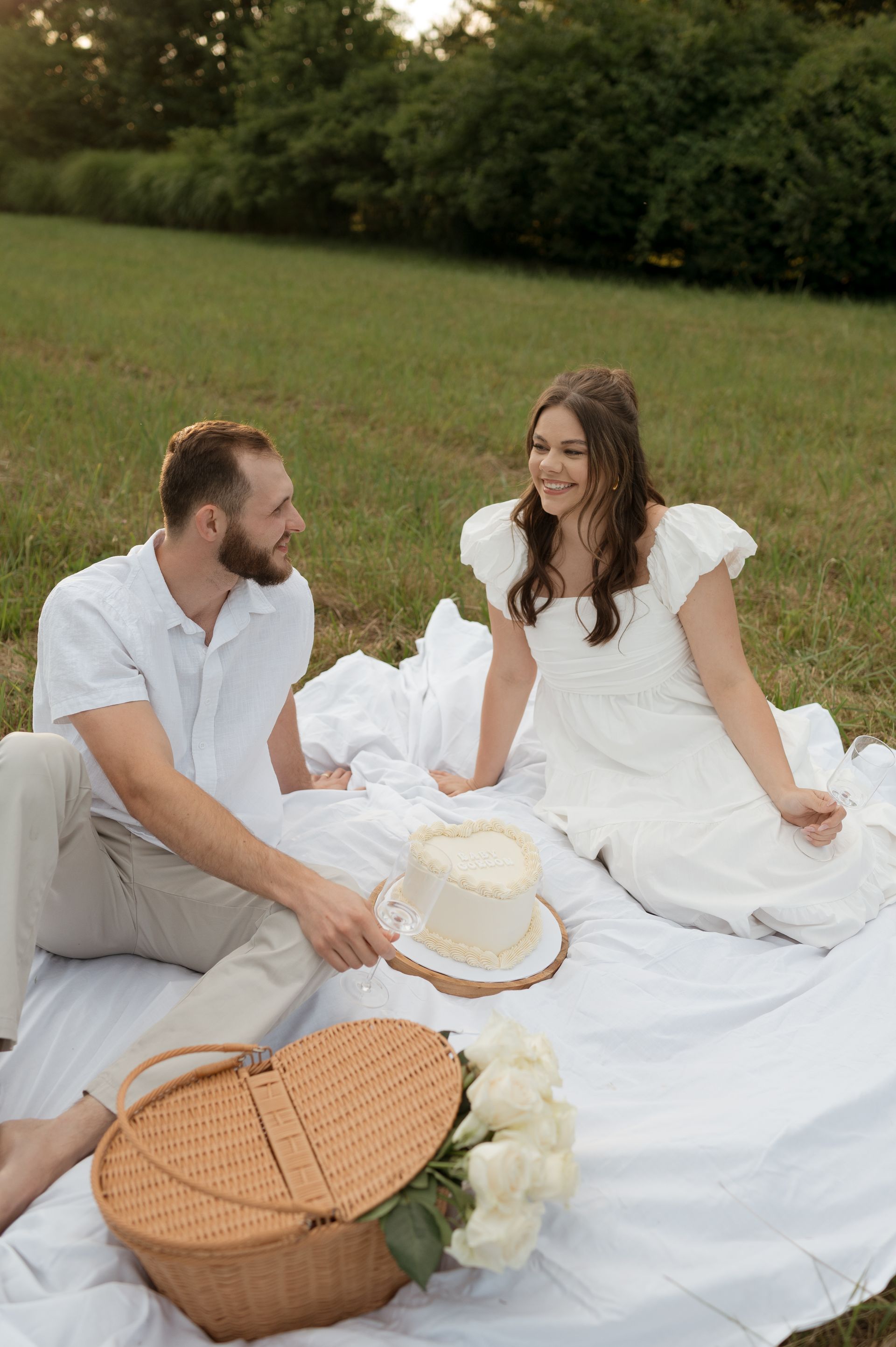 A man and a woman are sitting on a blanket in a field.