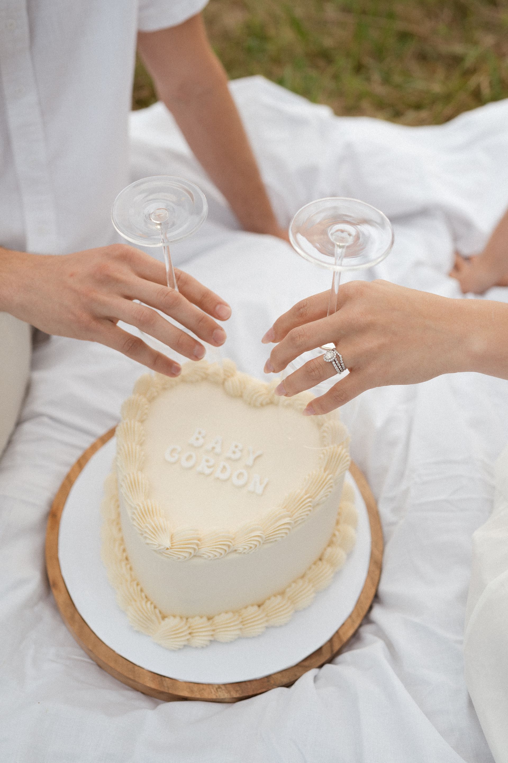A couple is toasting with champagne and a heart shaped cake.