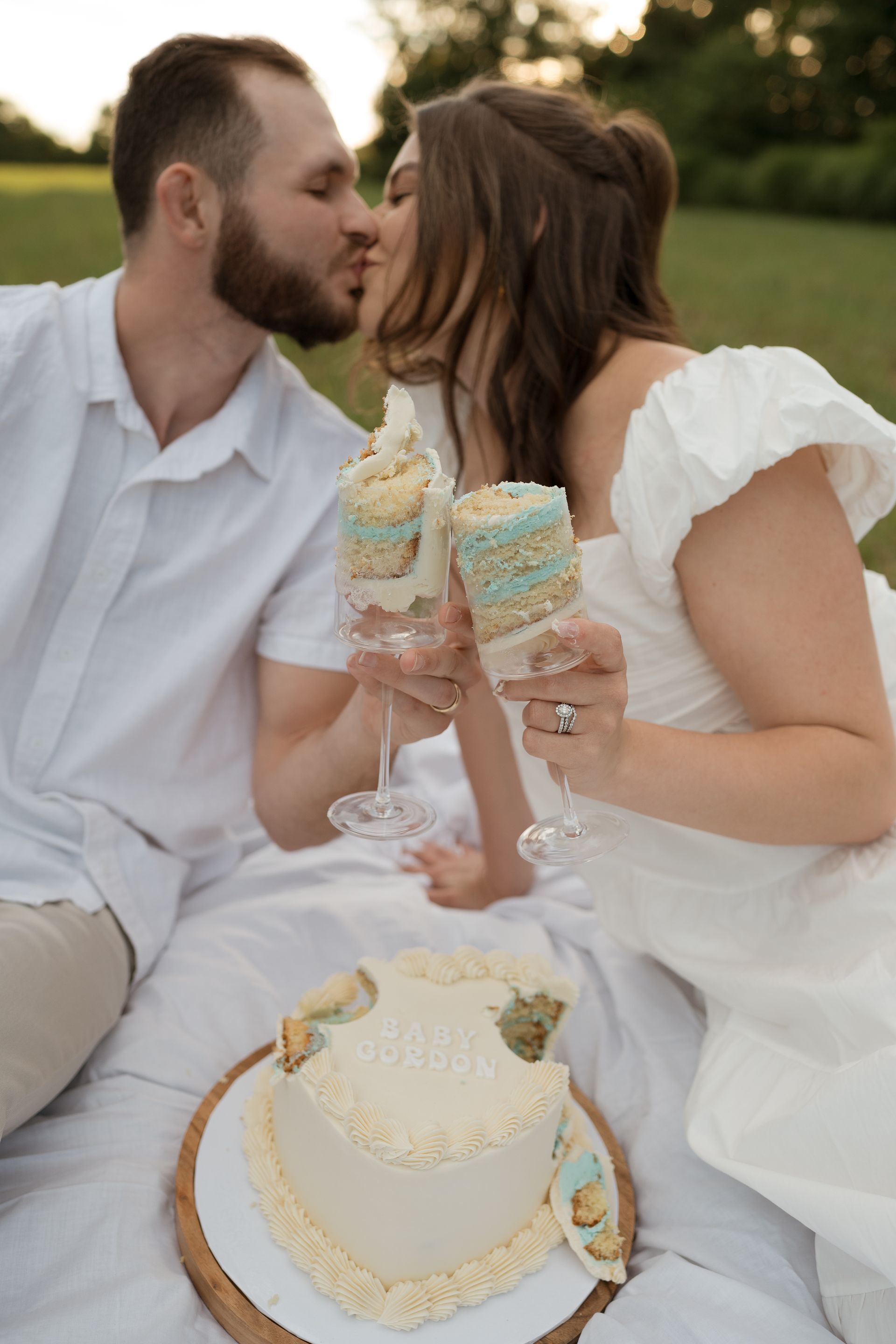 A man and a woman are kissing in front of a cake.