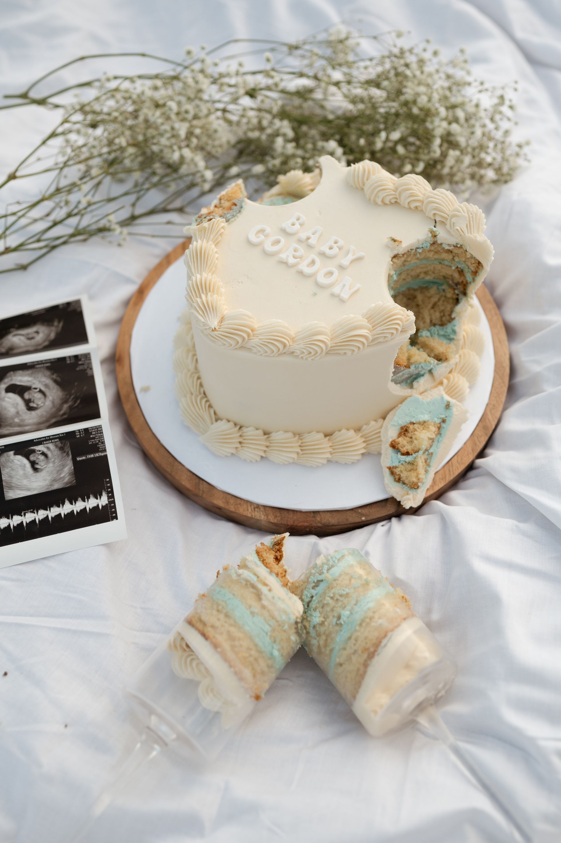 A baby shower cake with a bite taken out of it is on a table.