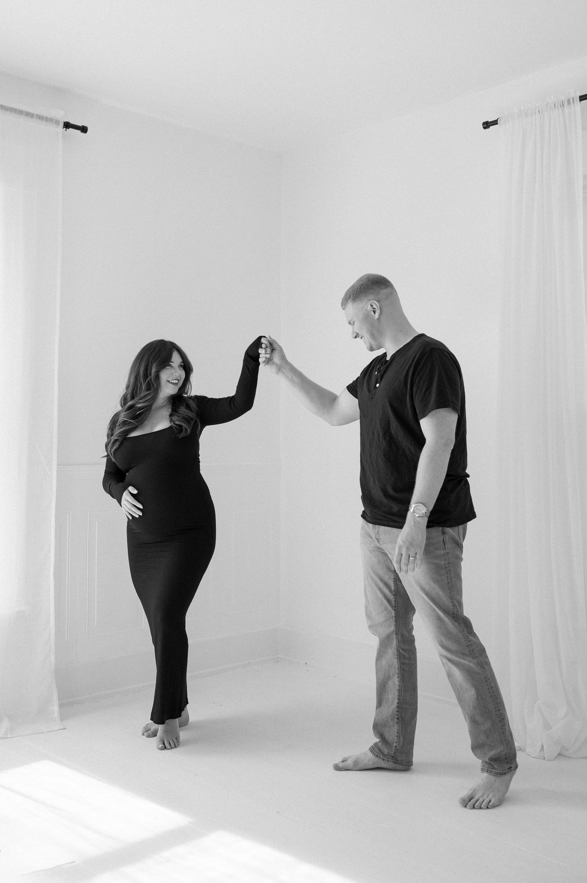 A man and a pregnant woman are dancing in a room.