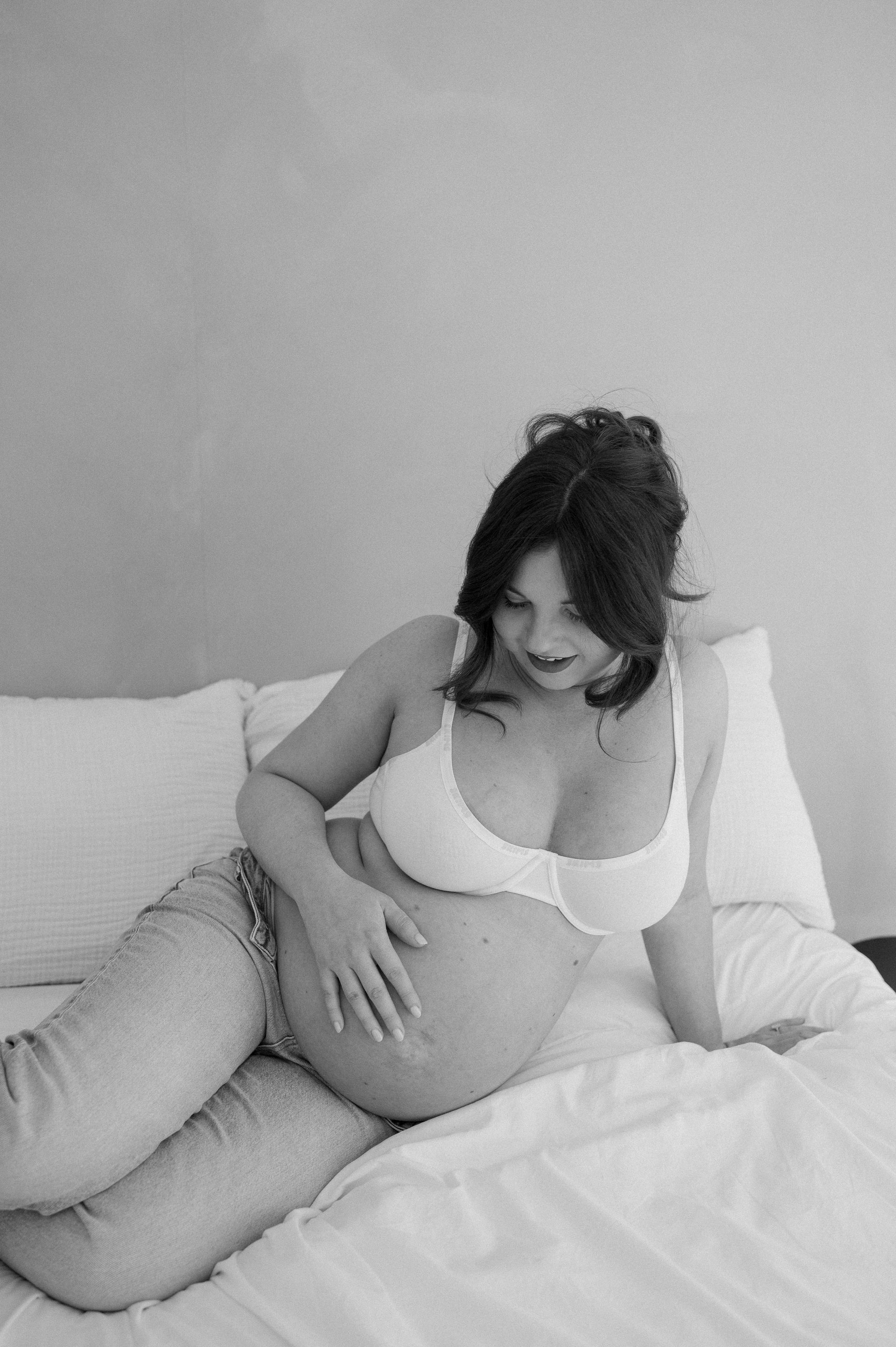 A black and white photo of a pregnant woman laying on a bed.