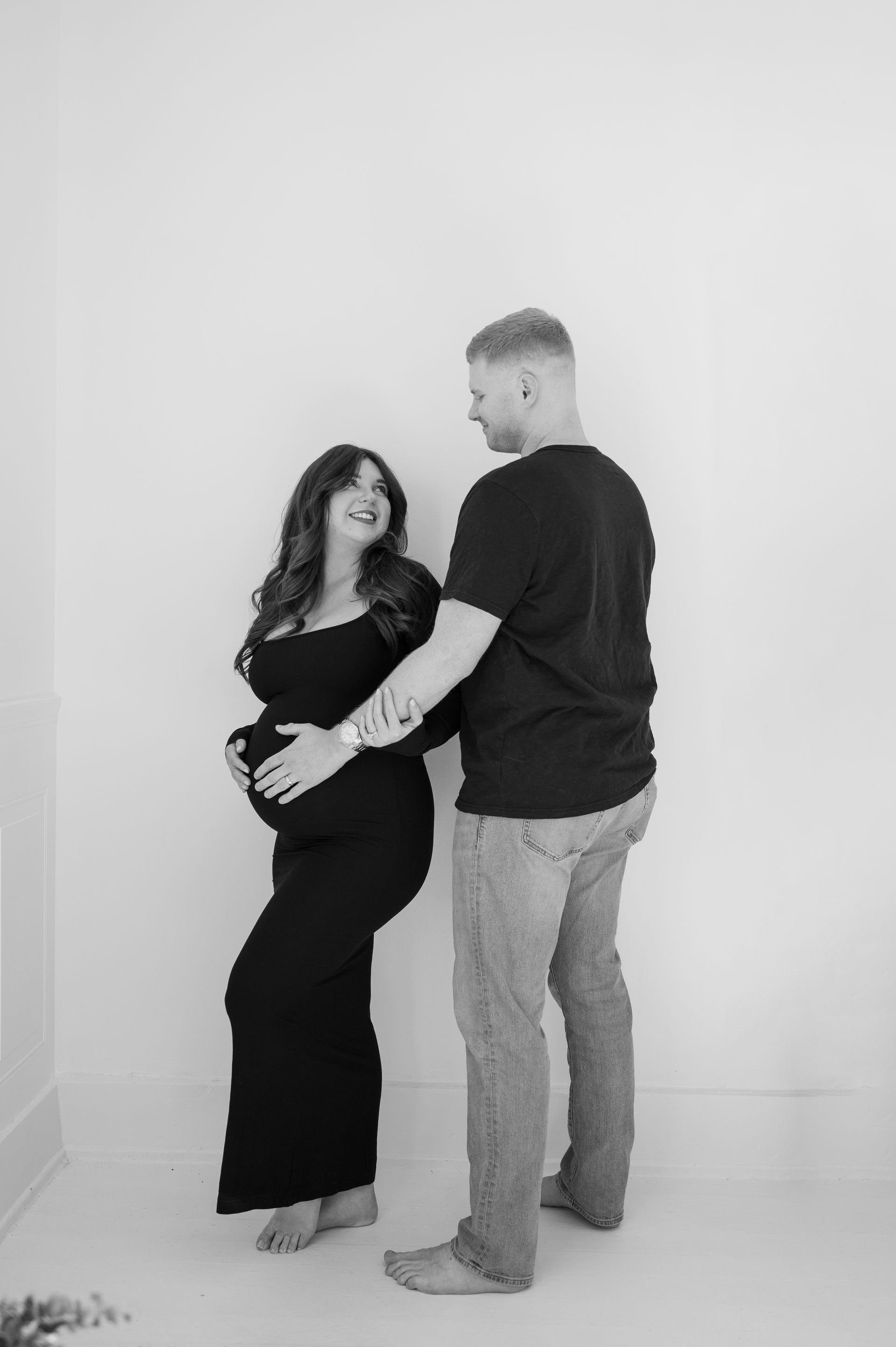A man is standing next to a pregnant woman in a black dress.