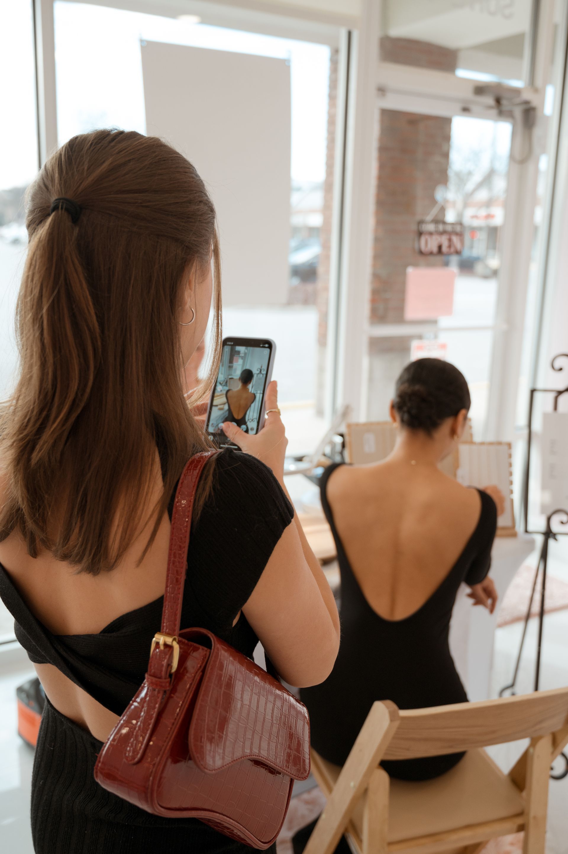 A woman taking a picture of another woman with her phone