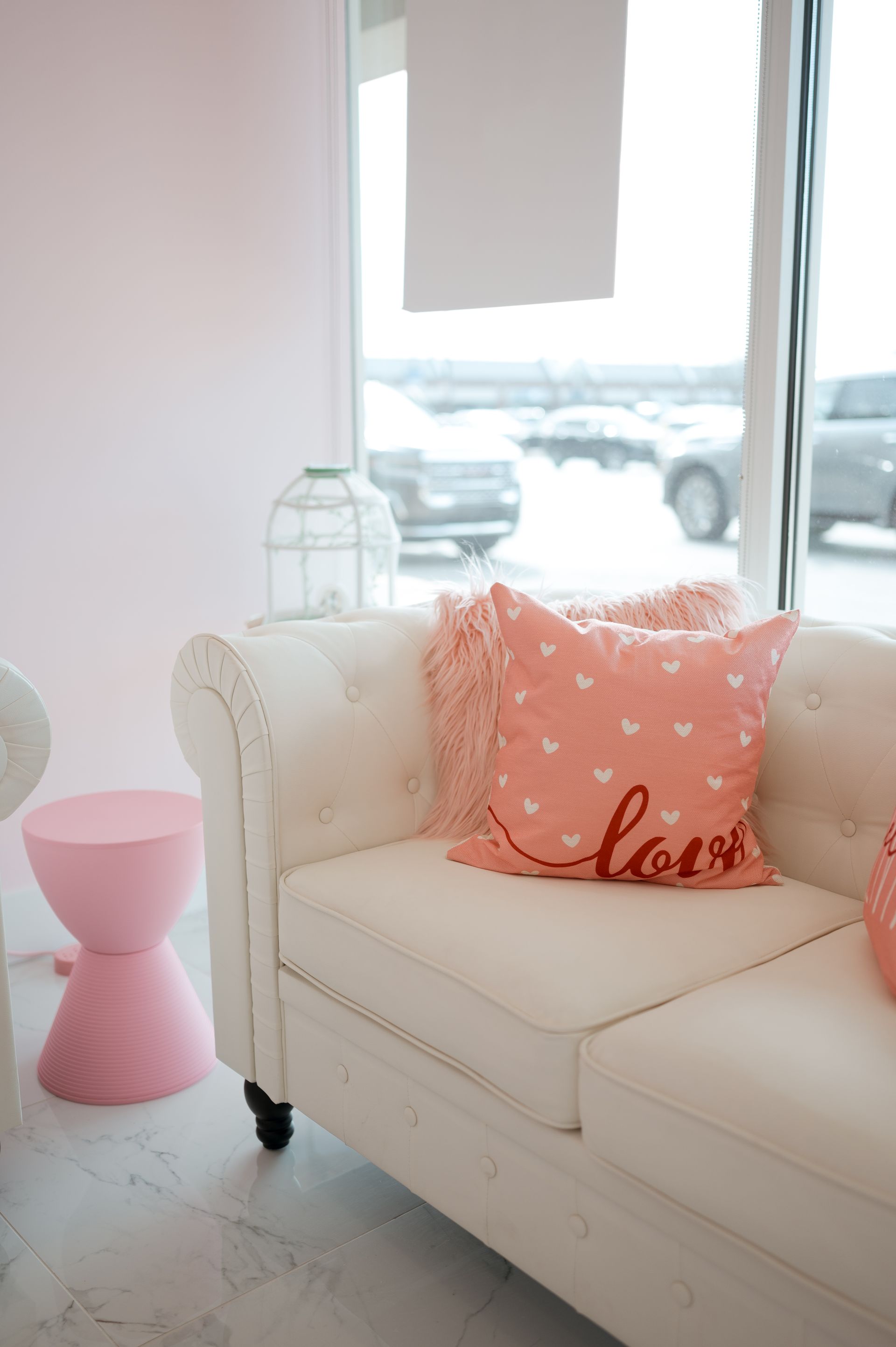 A white couch with a pink pillow that says love