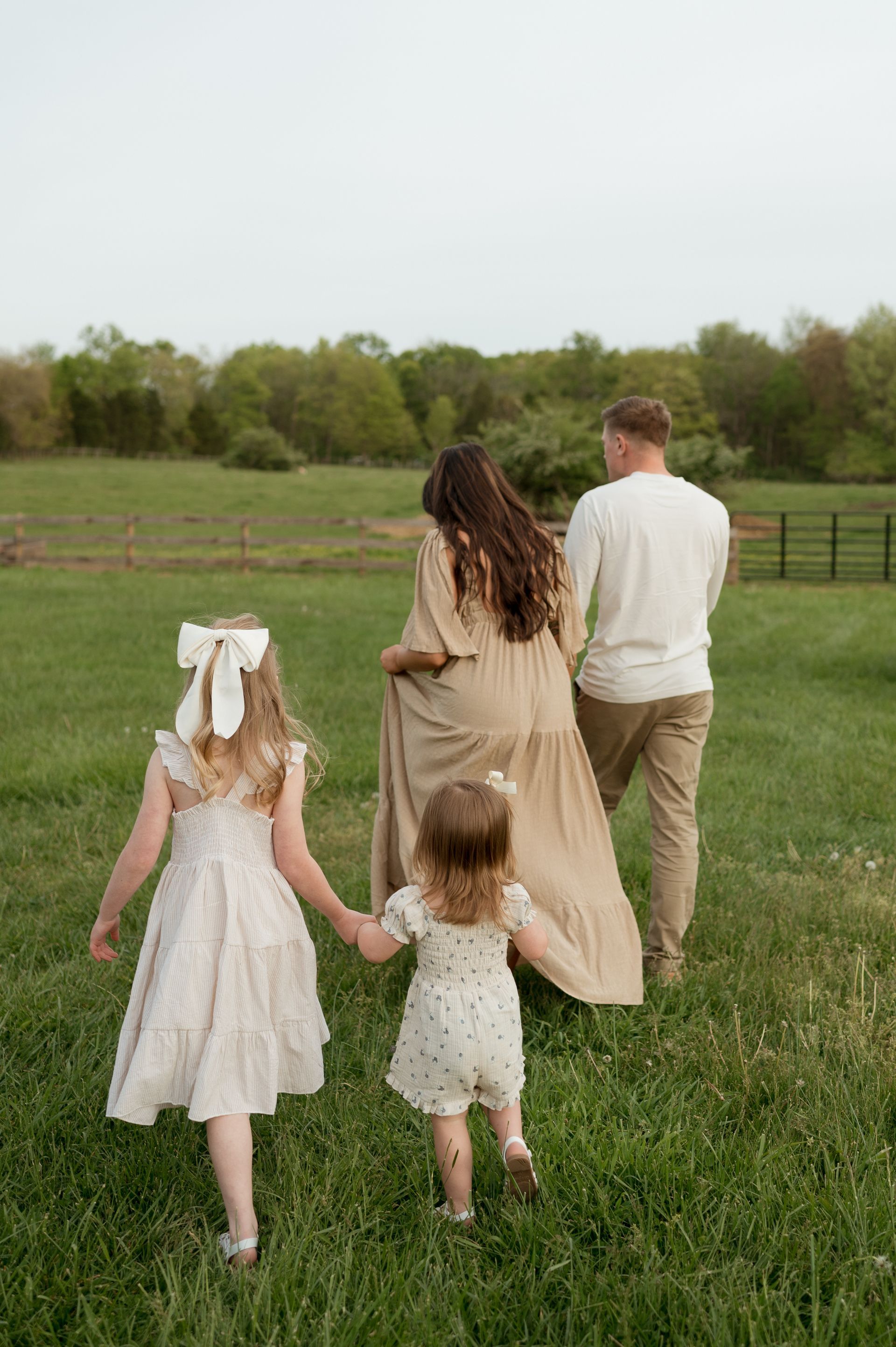 A family is walking through a grassy field holding hands.