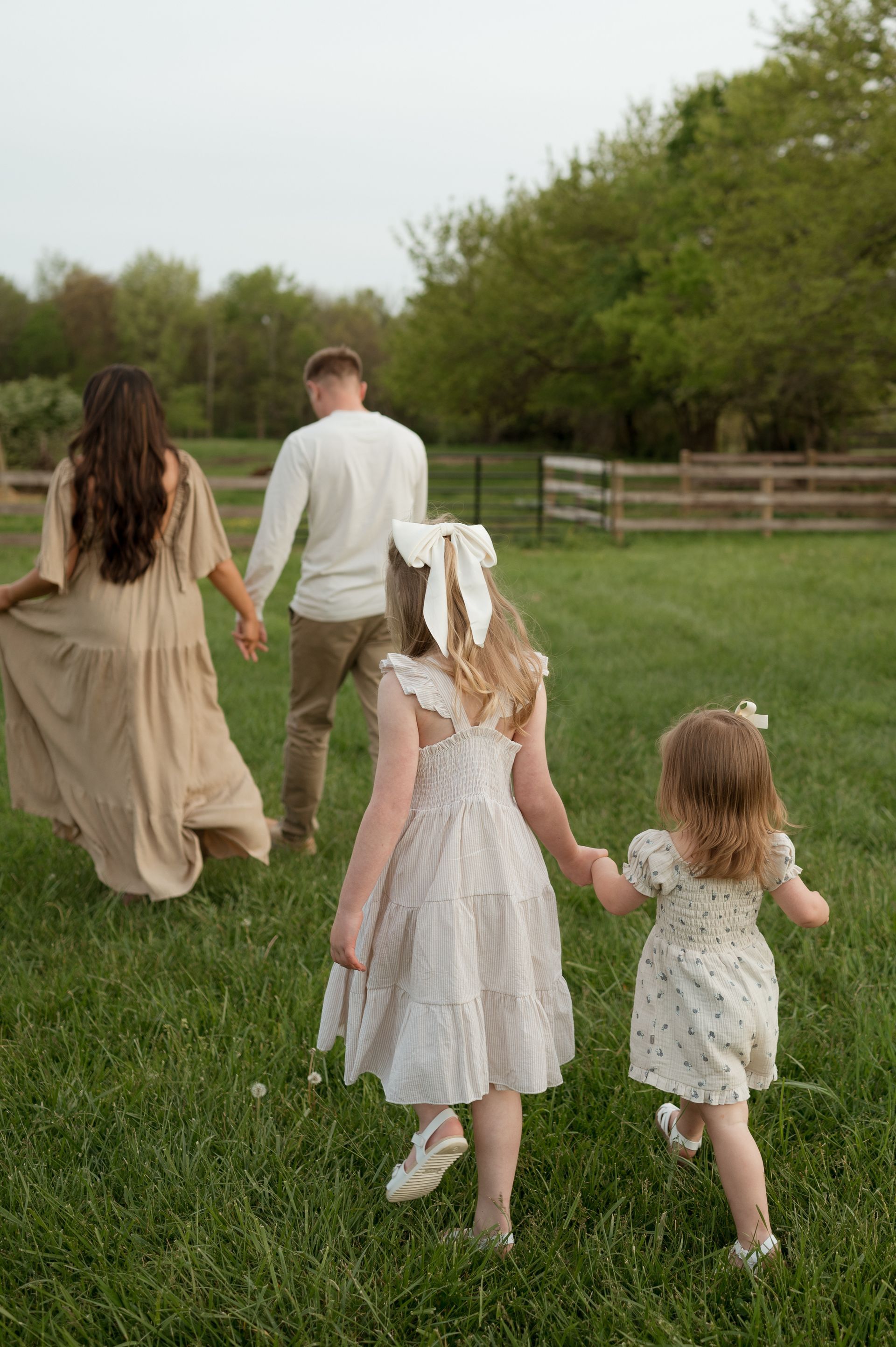 A family is walking through a grassy field holding hands.